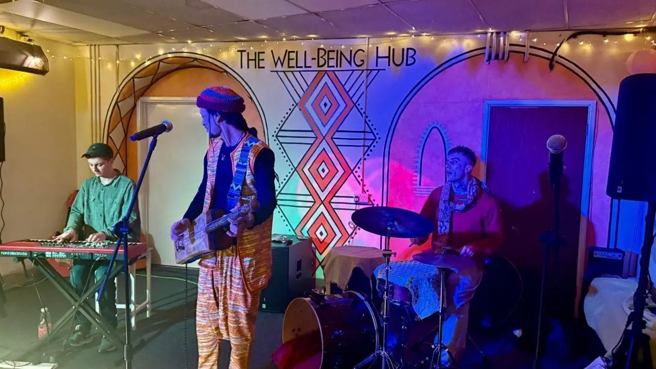 A band mid-performance under the stage lights at The Wellbeing Hub