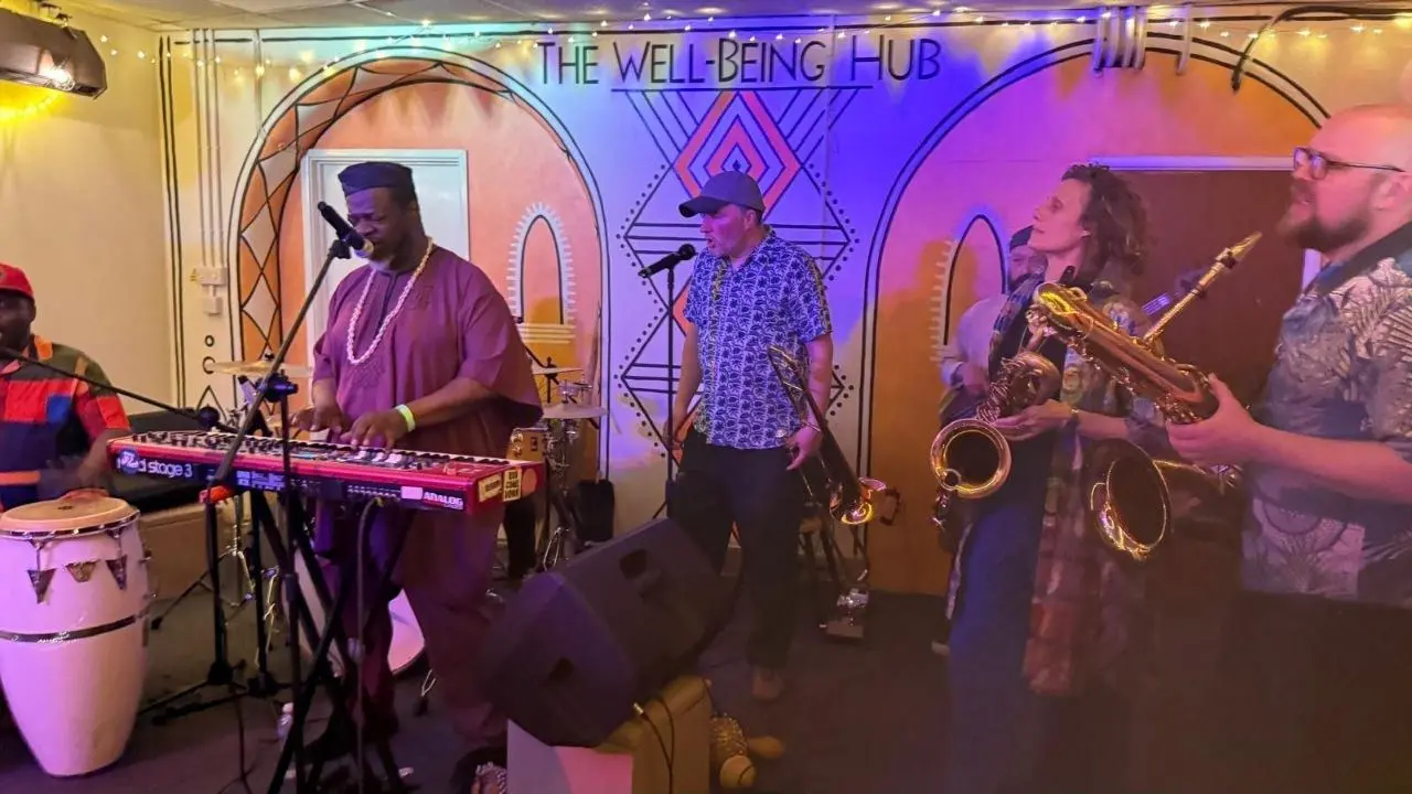 Dele Sosimi and his band across the full stage at The Wellbeing Hub