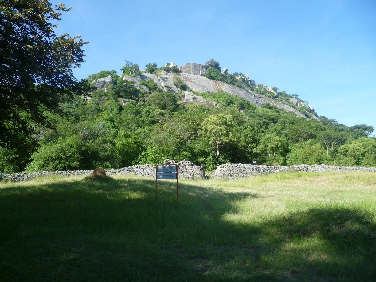 A wooded granite hill rising above open grassland