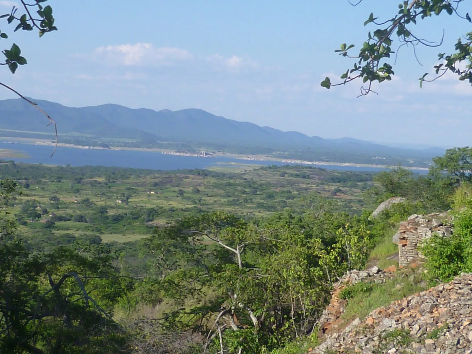 A distant lake beyond green bush and hills in Zimbabwe