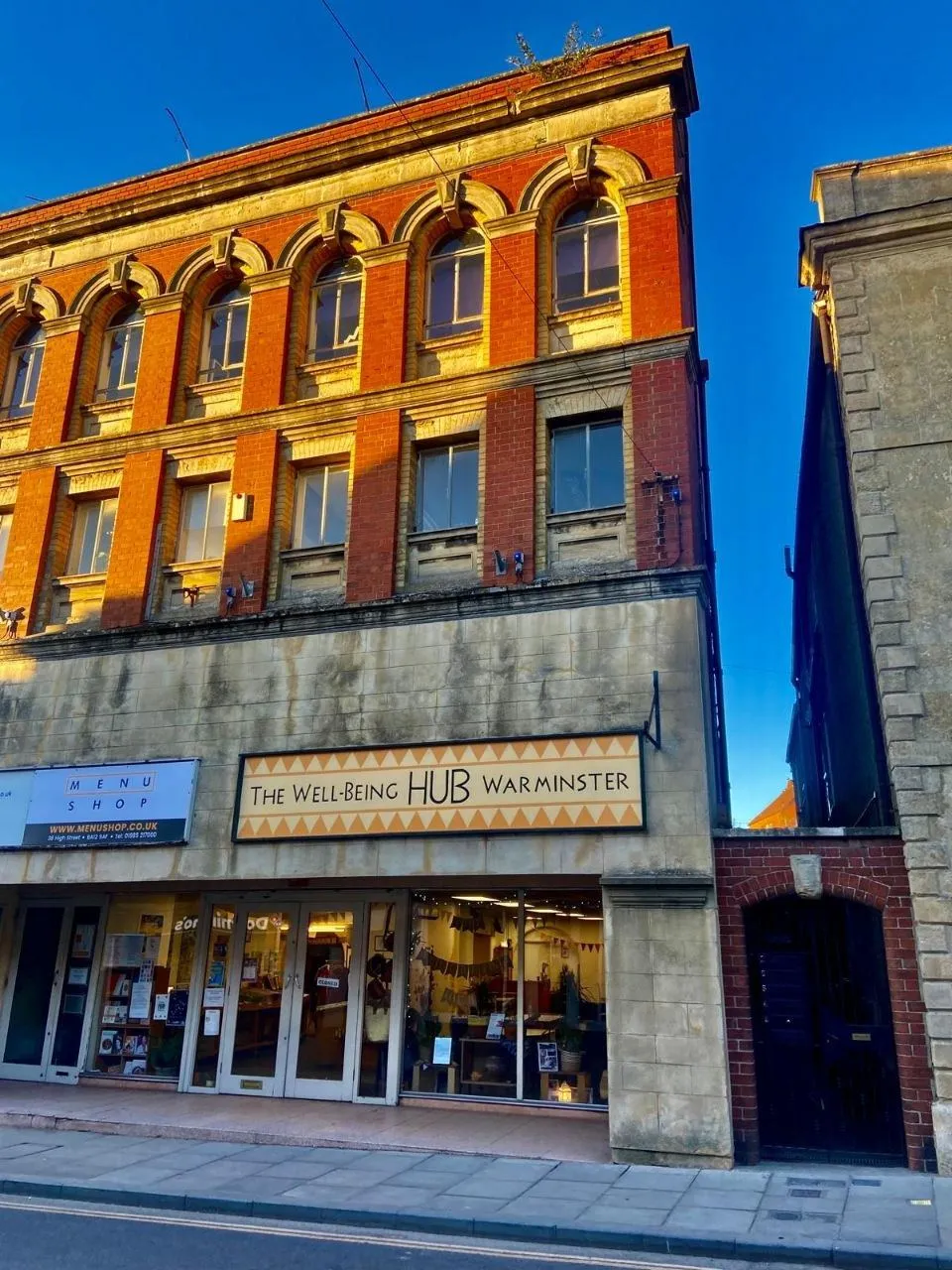 The Wellbeing Hub shopfront on Warminster High Street in evening light
