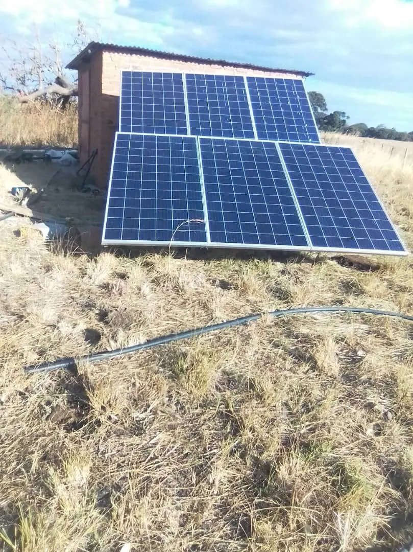 Solar panels set up on the ground beside a brick building